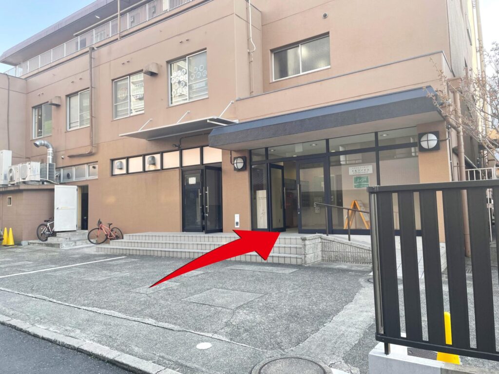 ⑧　右手に茶色のマンションが見えてきます。こちらからお入りください。